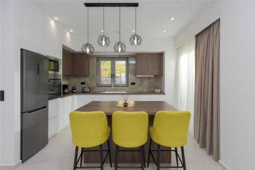 a kitchen with a wooden table and yellow chairs at Sunny Drops Villas by Estia in Balíon