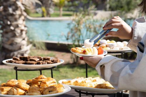 a woman holding a plate of food on a table at Oasis lodges in Marrakech