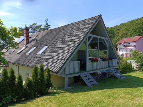 une maison avec un toit en gambrel et une terrasse couverte dans l'établissement Dom Marek, à Wisełka