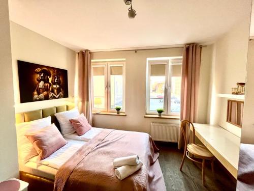 a bedroom with a bed and a desk and windows at Apartament Kameralny nad Motławą in Gdańsk