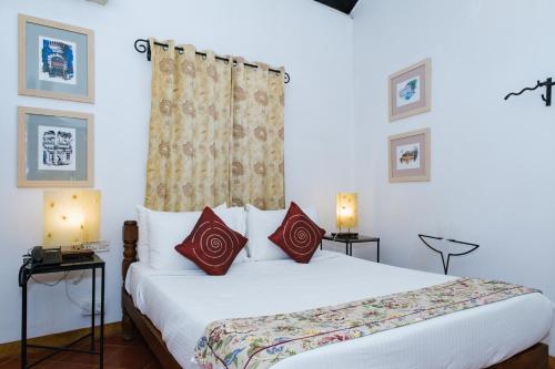 a bedroom with a large white bed with red pillows at Granpa's Inn Hotel Bougainvillea in Anjuna