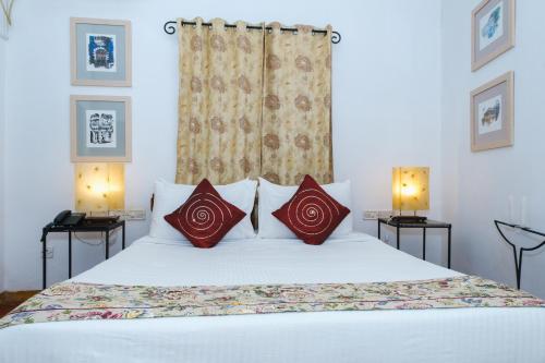 a bedroom with a white bed with red pillows at Granpa's Inn Hotel Bougainvillea in Anjuna