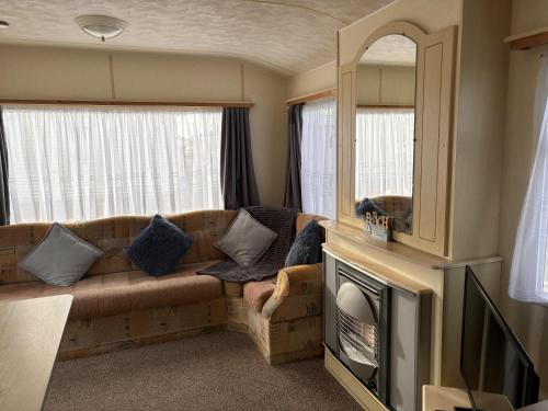 a living room with a couch and a mirror at Caravan Sleeps 4 with Free Parking in Burnham on Sea