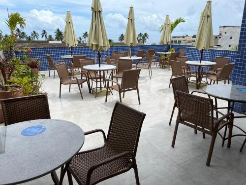 an outdoor patio with tables and chairs and umbrellas at Apartamento - Centro Porto de Galinhas in Escada