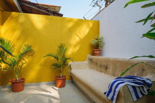 a yellow wall with potted plants and a bench at Granpa's Inn Hotel Bougainvillea in Anjuna