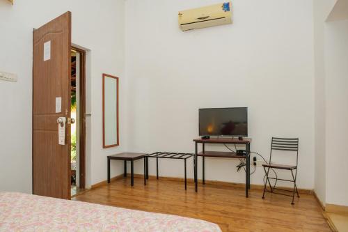 a bedroom with a television and a table and chairs at Granpa's Inn Hotel Bougainvillea in Anjuna