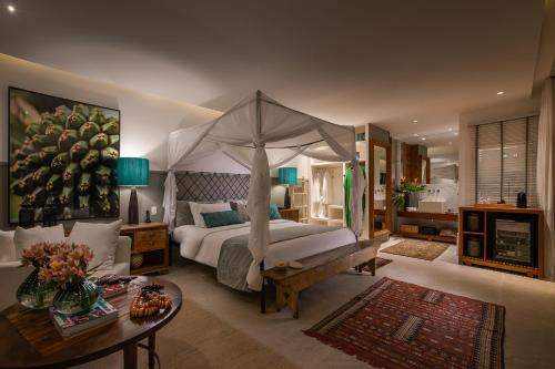 a bedroom with a canopy bed and a table at Vila deste Hotel in Búzios