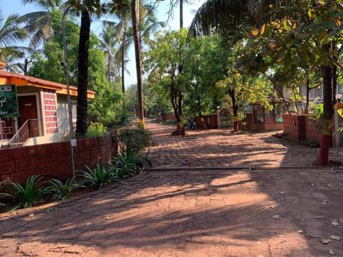 a dirt road with palm trees and a building at Dev Villa Dapoli in Dapoli