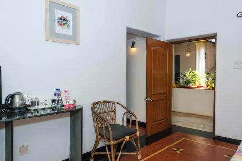 a room with a chair and a table and a door at Granpa's Inn Hotel Bougainvillea in Anjuna