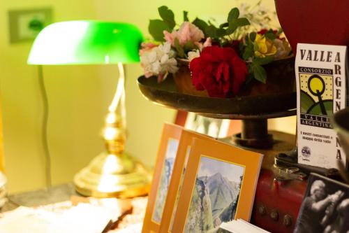 a table with a vase of flowers and a picture at Albergo Santo Spirito in Molini di Triora