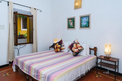 a bedroom with a bed with a striped comforter at Granpa's Inn Hotel Bougainvillea in Anjuna