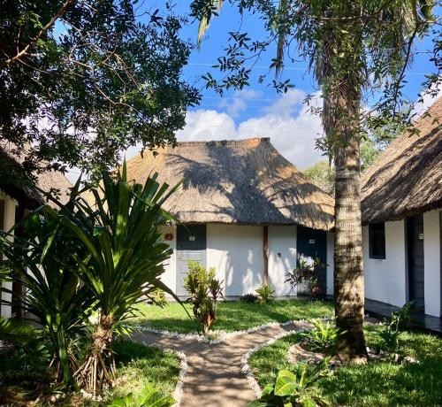 a house with a thatched roof and a pathway at Gecko Lodge, Dolphin Cottage in Vilanculos