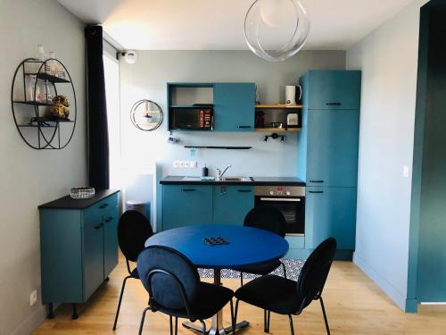 une cuisine avec des placards bleus et une table et des chaises bleues dans l'établissement Appart's Casa Mina, à Saint-Malo