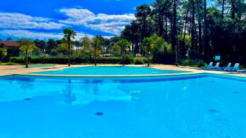 a large swimming pool with blue water at Chalet paisible à la plage, piscine et tennis in Ondres