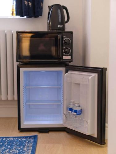 a microwave oven sitting on top of a refrigerator at Rofennie Suite -Luxury ensuite room! in Maidstone