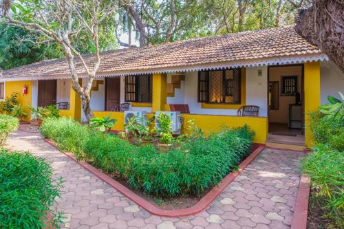 a yellow house with a pathway in front of it at Granpa's Inn Hotel Bougainvillea in Anjuna