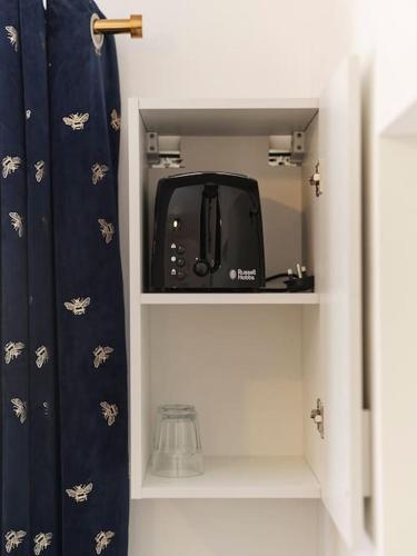 a black toaster sitting on a shelf in a kitchen at Rofennie Suite -Luxury ensuite room! in Maidstone