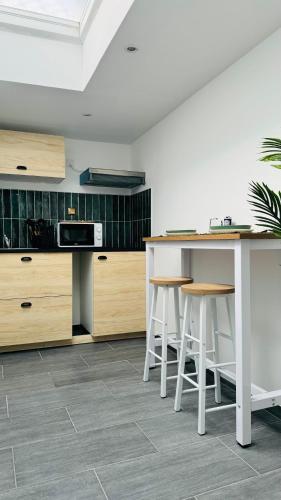 une cuisine avec des armoires en bois et un comptoir avec des tabourets dans l'établissement Secret Garden, à Roubaix