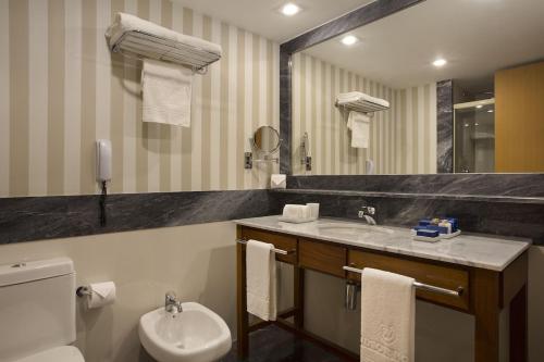 a bathroom with a sink and a toilet and a mirror at Apartamento Barra da Tijuca in Rio de Janeiro