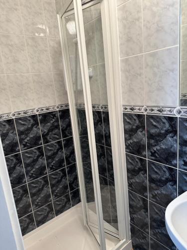 a bathroom with a shower with black and white tiles at Cosy Room in Shannon