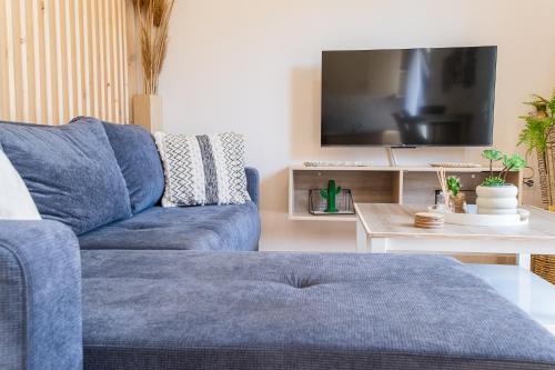 um sofá azul numa sala de estar com uma televisão em Casa Calida - 500m to Kos Town em Kaká Pinári