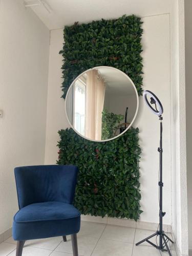 a mirror on a wall with a blue chair and a lamp at l'arc logement in Strasbourg