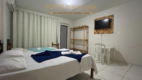 a bedroom with two beds and a tv on the wall at Hotel Novo Gama in Novo Gama