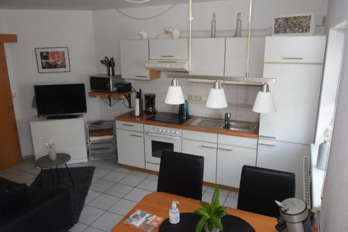 a kitchen with white cabinets and a table with chairs at Haus Luzia in Sankt Aldegund