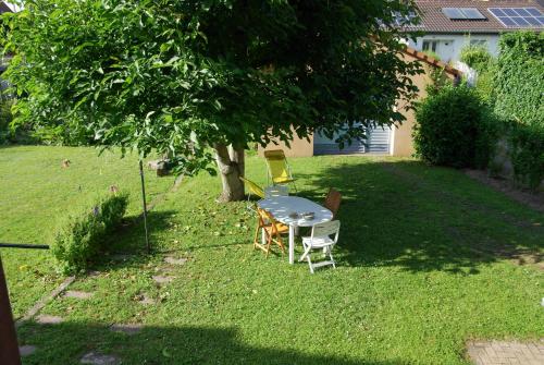La Maison de Vacances de Colmar et son jardin في كولمار: طاولة وكراسي في ساحة تحت شجرة