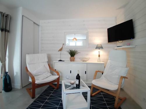 - un salon avec 2 chaises, une table et une télévision dans l'établissement Saint Georges de Didonne - LA PLAGE A 2 PAS - idéal pour un COUPLE avec ENFANTS, à Saint-Georges-de-Didonne