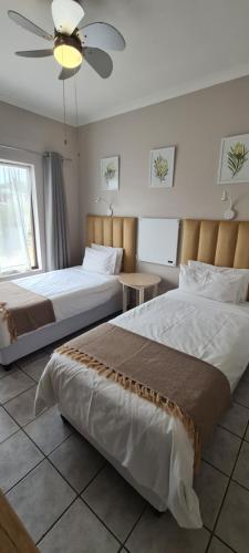 a bedroom with two beds and a ceiling fan at Greystone Guesthouse in Jeffreys Bay