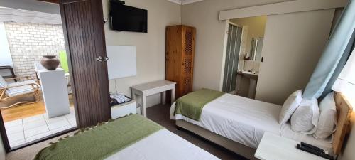 a small bedroom with a bed and a mirror at Greystone Guesthouse in Jeffreys Bay