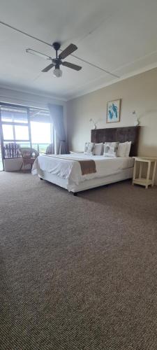 a bedroom with a large bed and a ceiling fan at Greystone Guesthouse in Jeffreys Bay