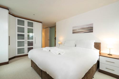 a bedroom with a large white bed with towels on it at Borough Flat with City Views by UnderTheDoormat in London