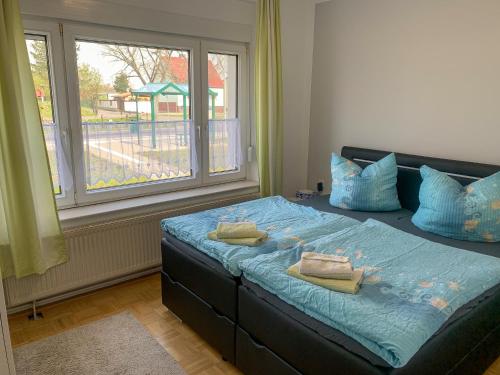 a bedroom with a bed with blue sheets and a window at Top-moderne Ferienwohnung auf früherem wunderschönen Bauernhof im Elbe-Elster-Kreis in Süd-Brandenburg in Schönewalde