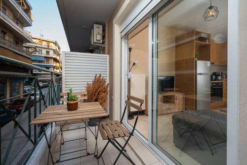 einen Balkon mit einem Holztisch und Stühlen darauf in der Unterkunft Lovebirds Nest 1BR Apt. 7' to Acropolis Metro in Athen