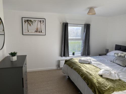 a bedroom with a bed with a dresser and a window at Charming 3 bedroom flint cottage in Lakenheath