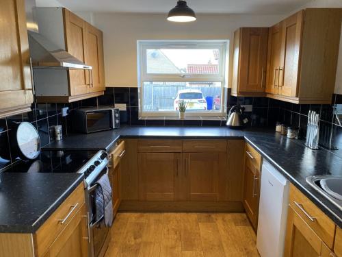 a kitchen with wooden cabinets and a window at Charming 3 bedroom flint cottage in Lakenheath