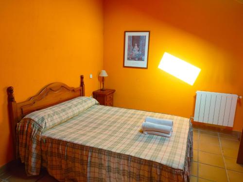 1 dormitorio con 1 cama con manta a cuadros en Alojamientos El Castillo, en El Berrueco