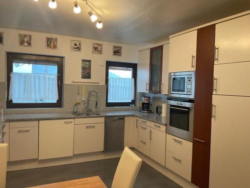 a kitchen with white cabinets and stainless steel appliances at Ferienwohnung Raevenhof in Ayl