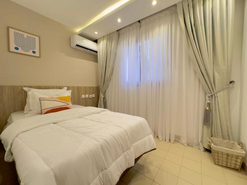 a bedroom with a white bed and a window at Swanky apartment in Douala