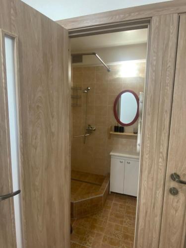 uma casa de banho com um chuveiro e um espelho. em White apartment em Kėdainiai