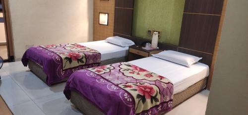 2 Betten in einem Hotelzimmer mit violetter Bettwäsche in der Unterkunft Hotel Mahendra in Jālgaon