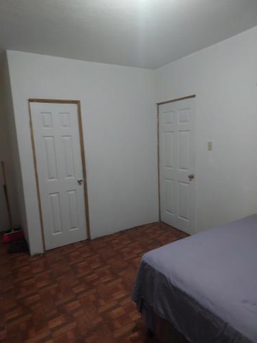 1 dormitorio con 2 puertas blancas y suelo de madera en Cómodo apartamento, en Amatitlán