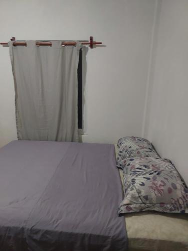 uma cama com uma almofada ao lado de uma janela em Cómodo apartamento em Amatitlán