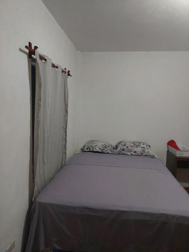 uma pequena cama num quarto com uma janela em Cómodo apartamento em Amatitlán