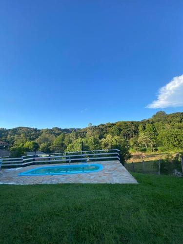 ein Schwimmbad im Gras neben einem Fluss in der Unterkunft Ranchinho Santa Luzia in Campos do Jordão