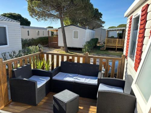 un patio con 2 sillas y un sofá en una terraza en Mobil home 6 à 8 personnes SANS Fun Pass, en Canet-en-Roussillon