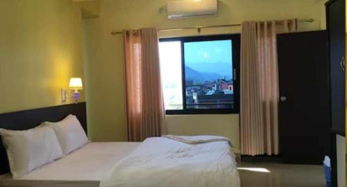 a bedroom with a bed and a large window at Hotel Suite Inn Lodge in Pokhara