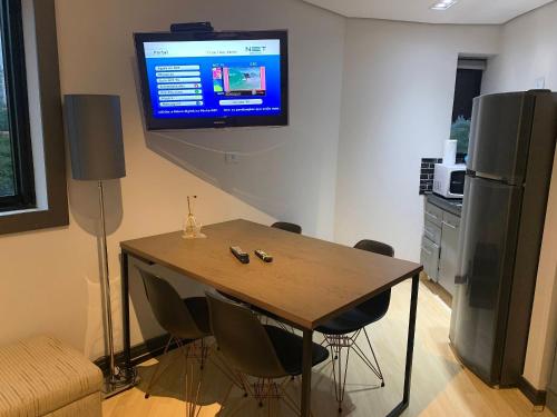 a kitchen with a table and a television on a wall at Get a Flat - 703 Luxo e Conforto - Ibirapuera in São Paulo